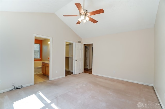 unfurnished bedroom featuring ensuite bath, a spacious closet, ceiling fan, light colored carpet, and a closet