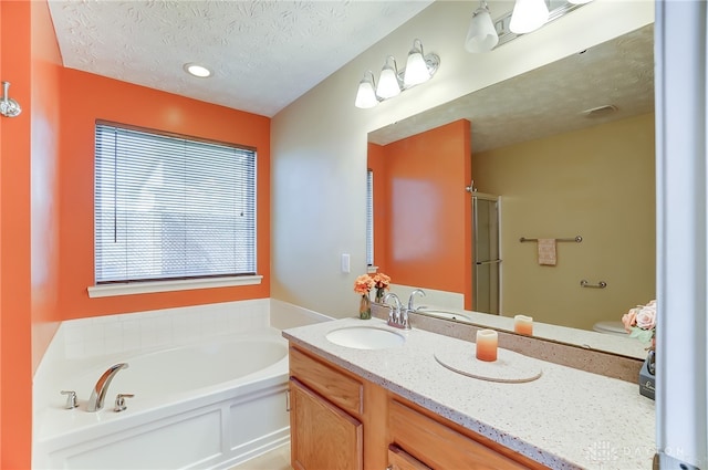 full bathroom with vanity, separate shower and tub, toilet, and a textured ceiling