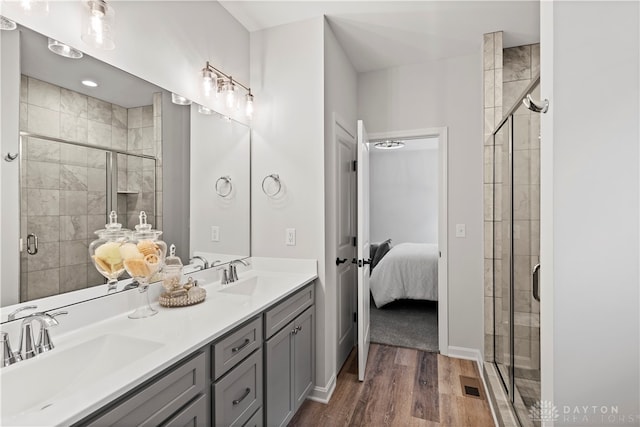 bathroom with double sink vanity, a shower with door, and hardwood / wood-style floors