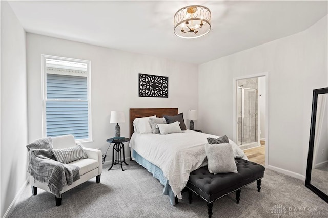 bedroom with connected bathroom, light colored carpet, and a notable chandelier