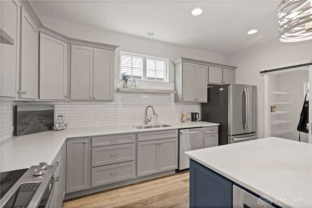 kitchen featuring appliances with stainless steel finishes, sink, tasteful backsplash, and light hardwood / wood-style floors