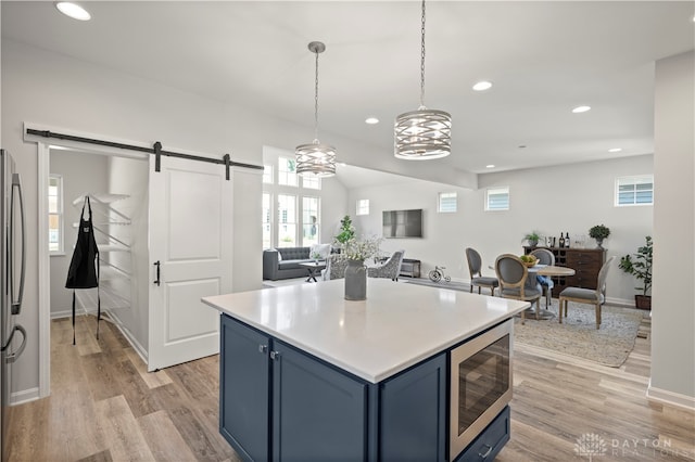 kitchen featuring blue cabinets, a barn door, stainless steel appliances, and light hardwood / wood-style flooring