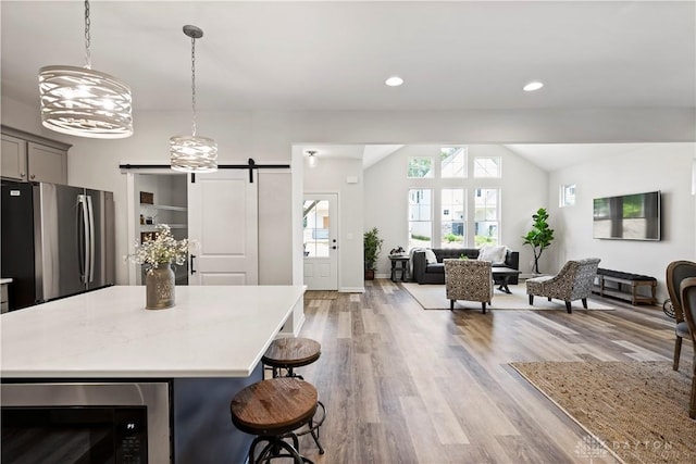 kitchen with built in microwave, a kitchen bar, gray cabinetry, stainless steel fridge, and a barn door