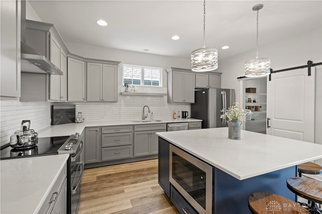 kitchen with a barn door, stainless steel appliances, sink, backsplash, and light hardwood / wood-style floors