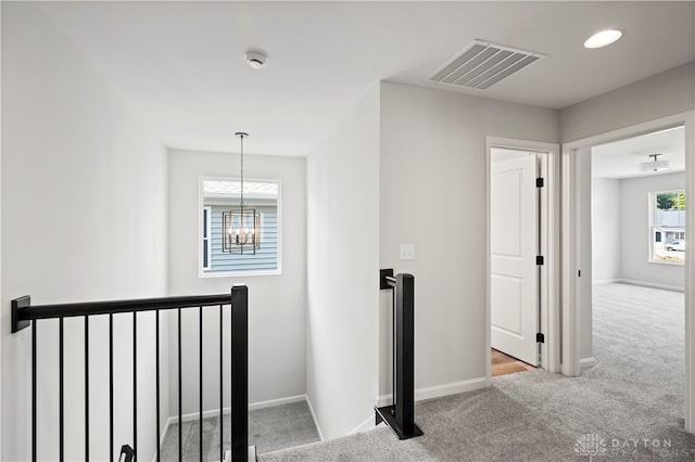 hallway with carpet flooring and a chandelier