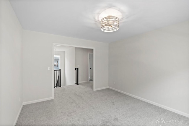 carpeted spare room featuring an inviting chandelier