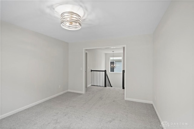 unfurnished room featuring carpet and a notable chandelier