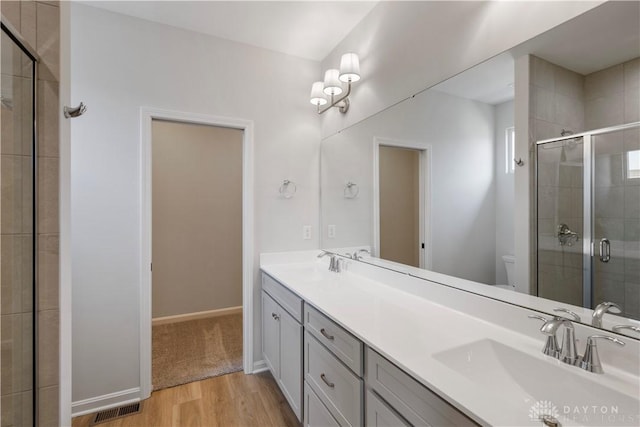 bathroom with wood-type flooring, dual bowl vanity, toilet, and walk in shower