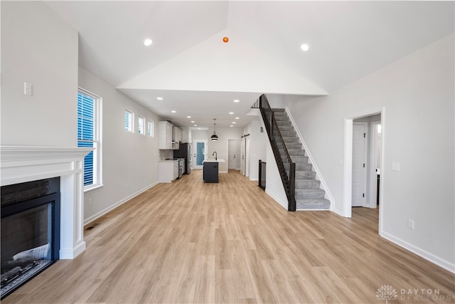 unfurnished living room with light hardwood / wood-style flooring and high vaulted ceiling