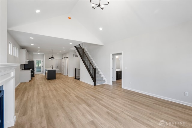 unfurnished living room with high vaulted ceiling, sink, and light hardwood / wood-style floors