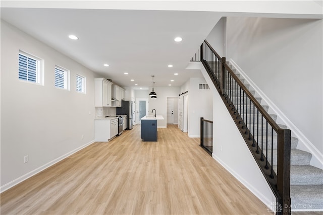 unfurnished living room featuring light wood-type flooring and a barn door