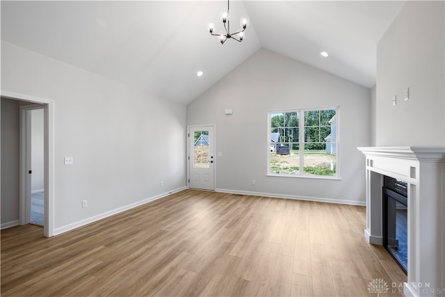 unfurnished living room featuring light hardwood / wood-style flooring, an inviting chandelier, and high vaulted ceiling