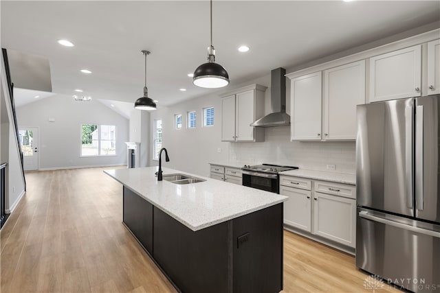 kitchen with appliances with stainless steel finishes, backsplash, light hardwood / wood-style flooring, sink, and wall chimney exhaust hood