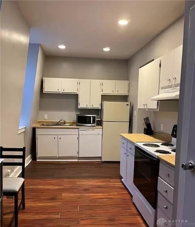 kitchen with white appliances, dark hardwood / wood-style flooring, and white cabinetry