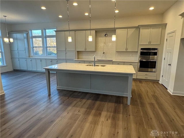 kitchen with pendant lighting, dark wood-type flooring, sink, decorative backsplash, and double oven