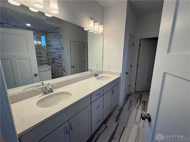 bathroom with a tile shower and vanity