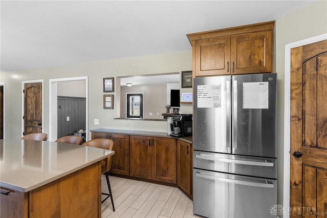 kitchen featuring light hardwood / wood-style flooring, a breakfast bar area, and stainless steel fridge