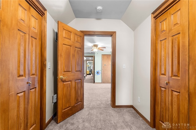 hall with lofted ceiling and light colored carpet