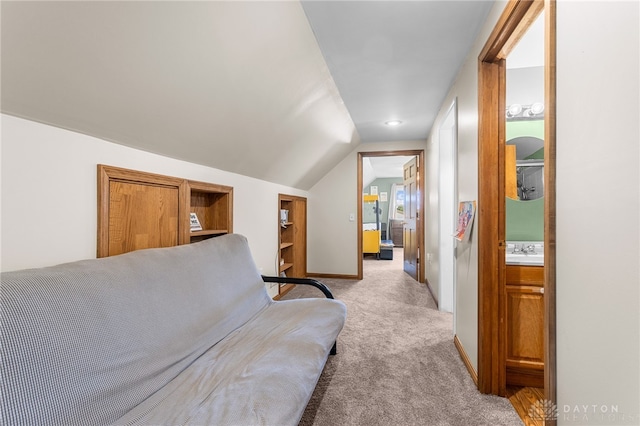 bedroom featuring ensuite bath, light colored carpet, sink, and lofted ceiling