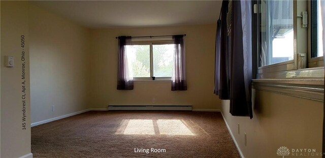 spare room featuring baseboard heating, carpet flooring, and a wealth of natural light