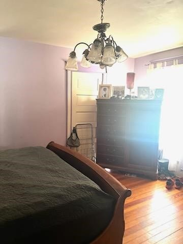 bedroom with wood-type flooring and a notable chandelier