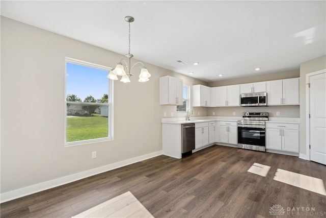 kitchen featuring white cabinets, appliances with stainless steel finishes, a notable chandelier, and dark hardwood / wood-style floors