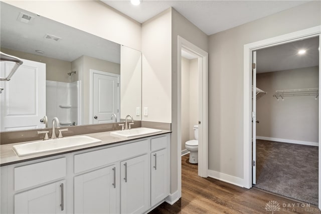 bathroom with vanity, toilet, wood-type flooring, and a shower