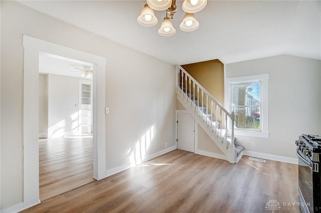 unfurnished living room featuring hardwood / wood-style floors, ceiling fan with notable chandelier, and built in features