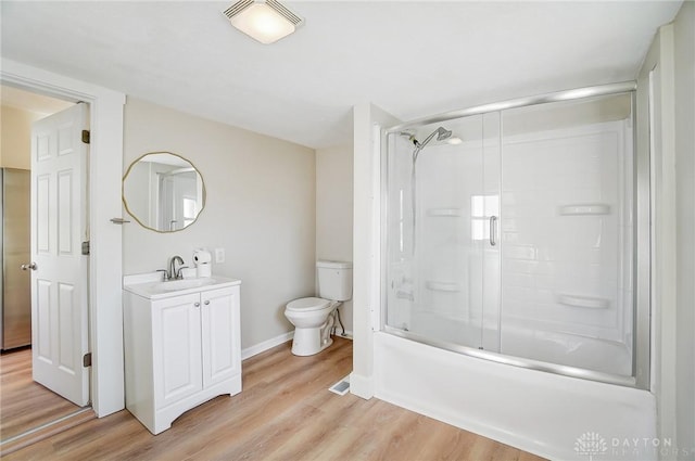 full bathroom with hardwood / wood-style floors, toilet, combined bath / shower with glass door, and vanity