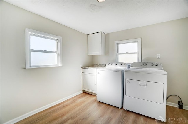 washroom featuring washing machine and dryer, cabinets, and light wood-type flooring