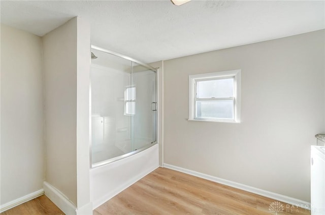 bathroom featuring shower / bath combination with glass door, a textured ceiling, and hardwood / wood-style flooring