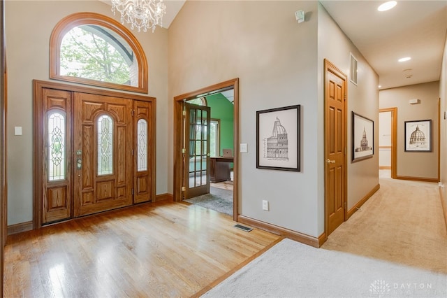 carpeted foyer featuring an inviting chandelier and a towering ceiling