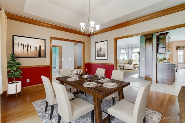 dining area featuring an inviting chandelier, a tray ceiling, and wood-type flooring