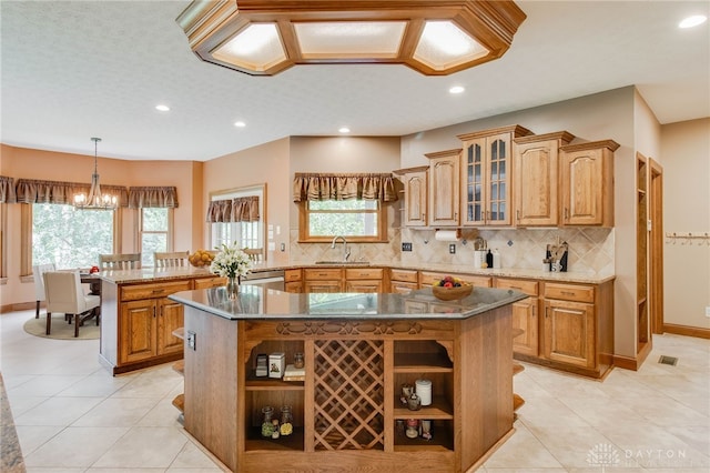 kitchen featuring light tile patterned flooring, tasteful backsplash, dark stone counters, and a center island