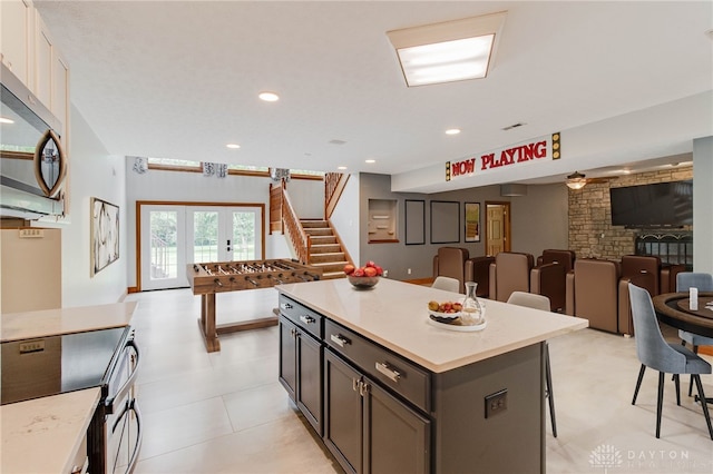 kitchen featuring appliances with stainless steel finishes, french doors, light tile patterned flooring, a kitchen breakfast bar, and a kitchen island