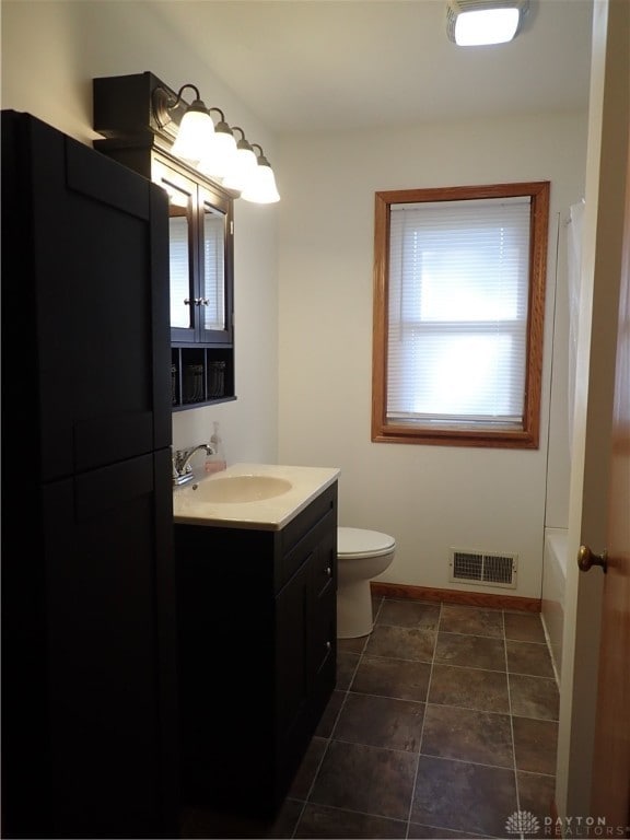 bathroom with vanity, toilet, tile patterned floors, and a bath