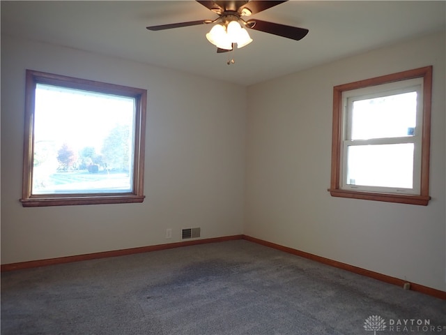 carpeted empty room featuring ceiling fan and a wealth of natural light