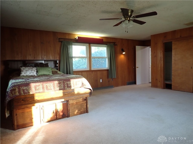 unfurnished bedroom with wooden walls, carpet floors, and ceiling fan