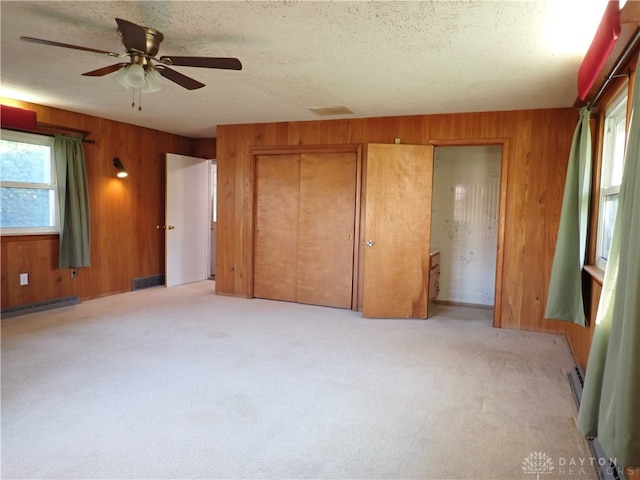 unfurnished bedroom featuring multiple windows, wooden walls, and ceiling fan