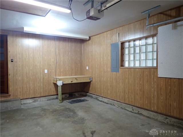 garage with wood walls, a garage door opener, and electric panel