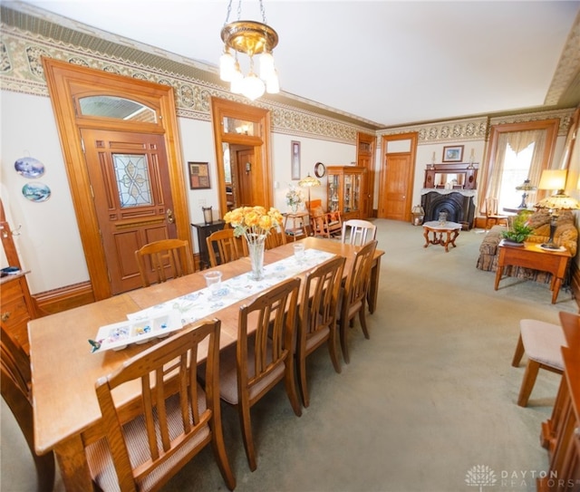 dining area featuring carpet, a notable chandelier, and ornamental molding