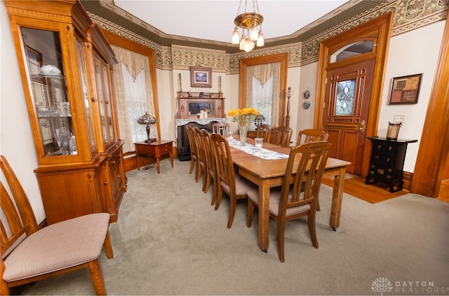 dining room with light carpet, crown molding, and an inviting chandelier