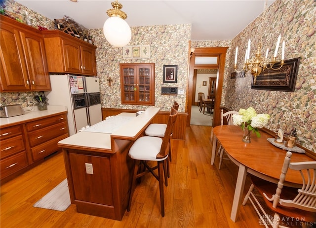 kitchen with a kitchen bar, pendant lighting, a center island, light hardwood / wood-style floors, and white fridge with ice dispenser