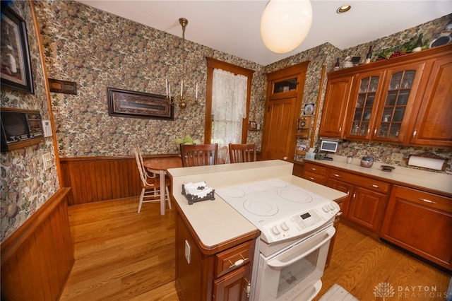 kitchen featuring white range with electric stovetop, wood walls, pendant lighting, and light wood-type flooring