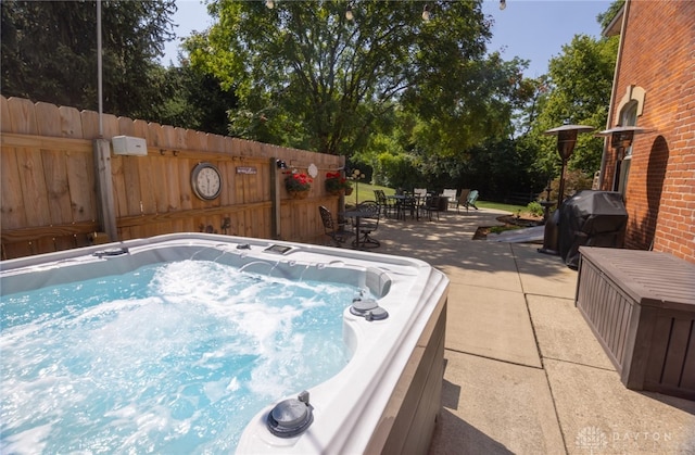 view of swimming pool featuring grilling area and a hot tub