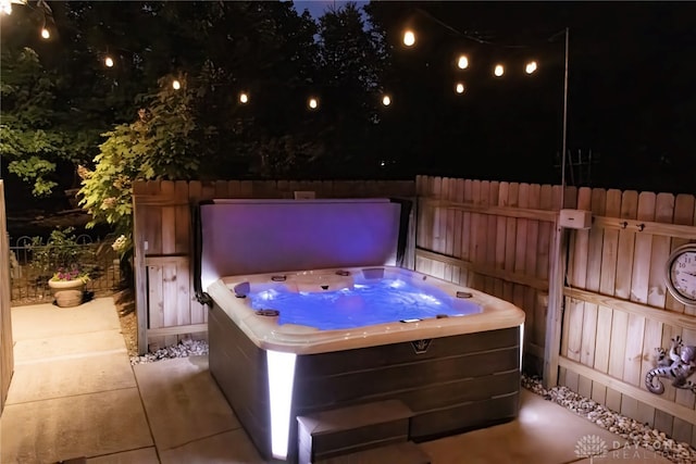 patio at twilight featuring a hot tub