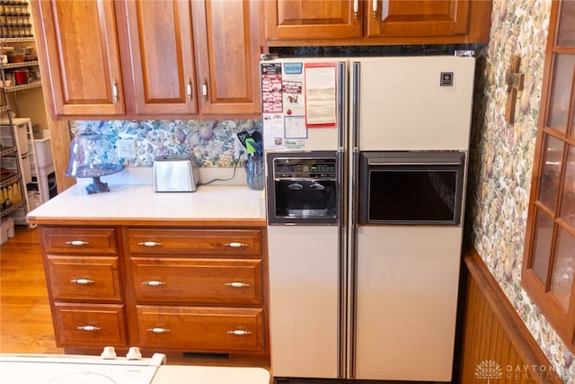 kitchen featuring white fridge with ice dispenser and light hardwood / wood-style flooring