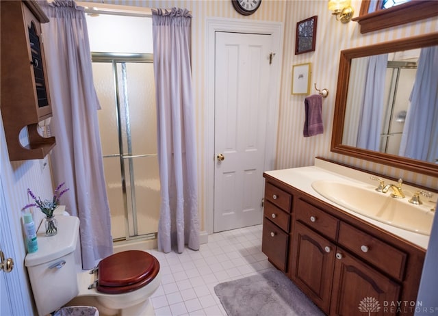 bathroom with tile patterned floors, a shower with door, vanity, and toilet