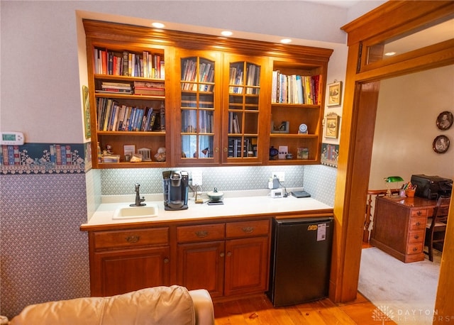 kitchen with black refrigerator, sink, built in features, and light hardwood / wood-style flooring