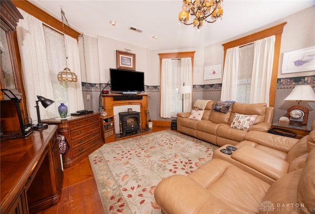 living room with a chandelier, hardwood / wood-style floors, and a wood stove